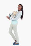 Side view of young woman carrying a pile of books