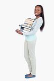 Side view of smiling young woman carrying a stack of books