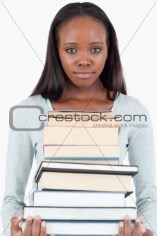 Sad looking young woman with pile of books