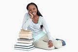 Smiling young woman leaning against a pile of books