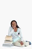 Smiling young woman leaning against a stack of books