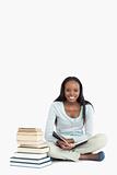 Smiling young woman sitting next to a pile of books