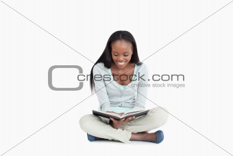 Young woman sitting on the floor reading a book