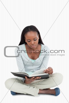 Young woman sitting on the floor turning the page of her book