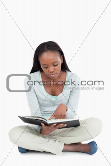 Young woman sitting on the floor focused on her book