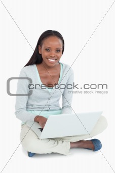 Smiling young woman with laptop on the floor