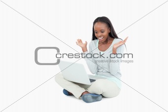 Young woman on the floor positive surprised by her laptop