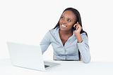 Smiling businesswoman making a phone call while using a laptop