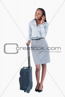 Portrait of a cute businesswoman with a suitcase making a phone call