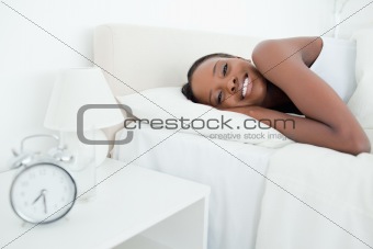 Woman waking up with her alarm clock