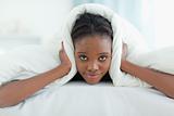 Woman covering her ears with a duvet