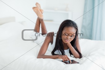 Woman using a tablet computer while lying on her bed