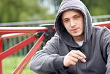 Young Man Sitting In Playground Smoking Joint