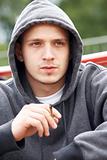 Young Man Sitting In Playground Smoking Joint