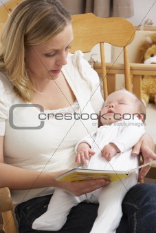 Mother Reading Story To Baby In Nursery