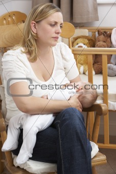 Worried Mother Breastfeeding Baby In Nursery