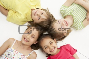 Circle of four young friends lying down smiling