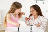 Two Young Girls Brushing Teeth at Sink