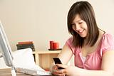 Smiling Teenage Girl using Mobile Phone at Home