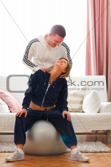 Young man helping his pregnant wife doing sport exercise at home
