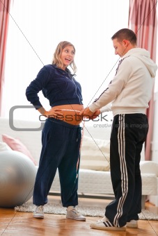 Husband measuring his pregnant wifes belly after fitness exercises
