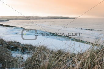 coastal snow covered links golf course at sunset