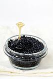 Black caviar in a glass jar on a white background
