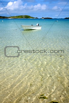 A white boat floating on clear sea, Isles of Scilly, Cornwall.