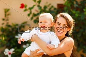 Portrait of smiling mother with baby on street
