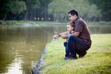 Happy Young Ethnic Father and Son Fishing at the Lake.