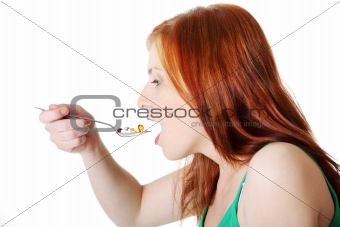 Teen girl taking pills from spoon.