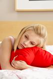 Sad Teenage Girl In Bedroom Hugging Pillow