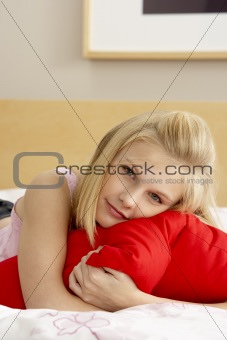 Teenage Girl In Bedroom Hugging Pillow