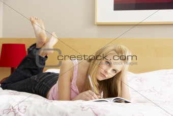 Teenage Girl Writing In Diary In Bedroom