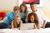 Group Of Five Teenage Using Laptop In Bedroom