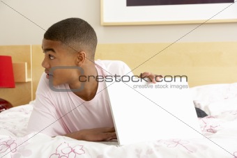 Guilty Teenage Boy Using Laptop In Bedroom