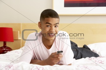 Teenage Boy In Bedroom With Mobile Phone