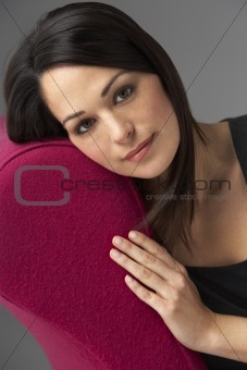 Studio Portrait Of Woman Relaxing On Pink Chaise Longue