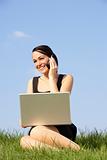 Woman Using Laptop And Mobile Phone Outdoors In Countryside