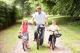 Father and children riding bikes in countryside