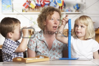 Adult Helping Two Young Children at Montessori/Pre-School