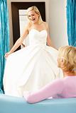 Bride trying on wedding dress with sales assistant