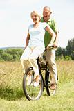 Mature couple riding bike in countryside