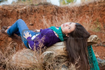 Shot of a young woman lying on log 