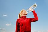 Young woman drinking water from plastic bottle