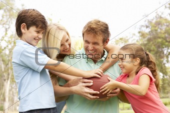 Family Playing American Football Together In Park