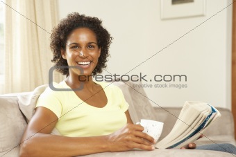 Woman Reading Book With Drink At Home