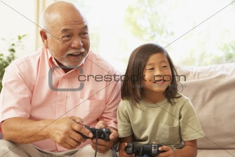 Grandfather And Grandson Playing Computer Game At Home
