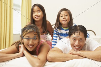 Young Family Relaxing In Bedroom