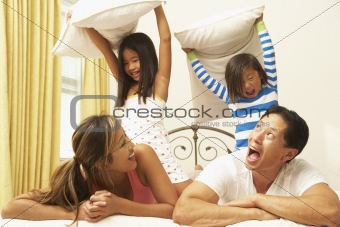 Young Family Having Pillow Fight In Bedroom